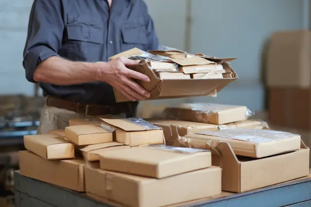 Worker carrying a tray of packed parcels in a shipping room
