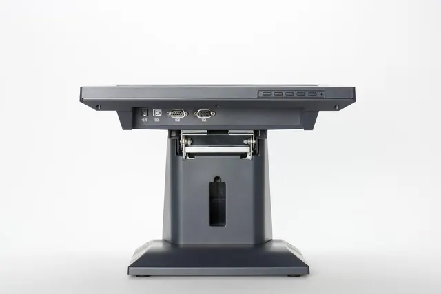 Gray touchscreen POS terminal on a sturdy stand, seen from below with USB, COM and VGA ports, on a white background