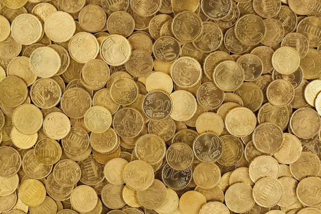 Overhead view of a large pile of gold-colored 10 and 20 euro cent coins scattered across the frame