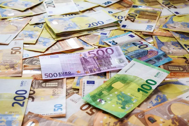 Scattered euro banknotes in 20, 50, 100, 200 and 500 denominations covering a flat surface