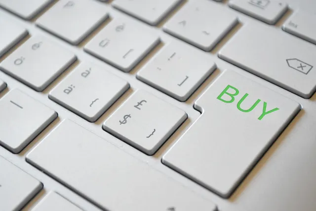 Close-up of a silver laptop keyboard with a green BUY label on the enter key, beside dollar and pound sign keys