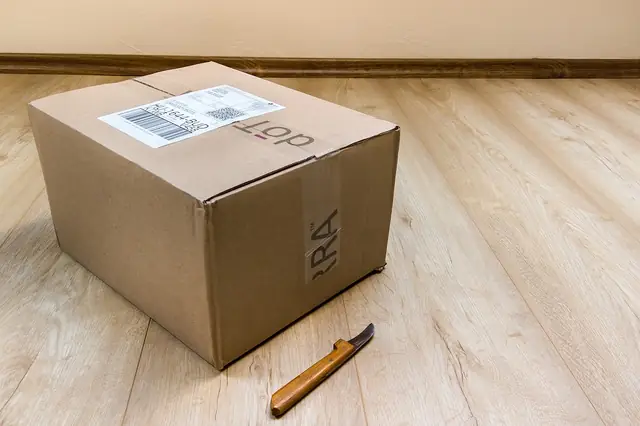 Sealed cardboard parcel with shipping label on a wooden floor