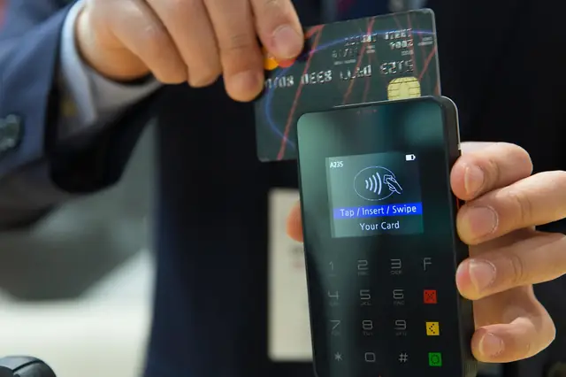 Card being inserted into a handheld card payment terminal