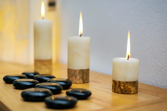 Lit candles and smooth black massage stones on a table