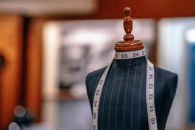 Tailor's mannequin in navy pinstripe fabric with a measuring tape draped around its neck in a softly lit shop