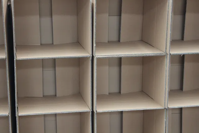 Wall of empty open cardboard shipping boxes stacked in a grid, their open sides facing the camera