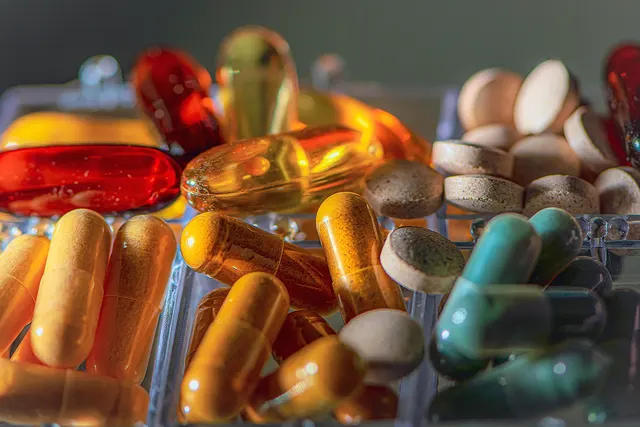 Close-up of assorted supplement capsules, softgels and tablets sorted in a clear plastic pill organizer