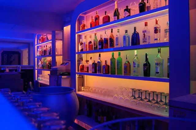 Bar shelves of liquor bottles lit in blue and orange