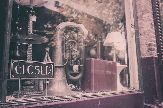 Shop window displaying a closed sign and vintage brass tuba