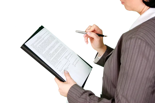 Person in a pinstripe suit holding a pen while reviewing a printed document on a clipboard against a black background