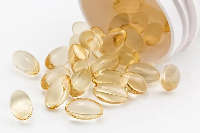 Clear golden softgel capsules spilling from a bottle