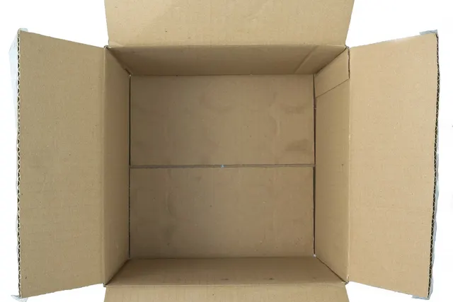 Top-down view of an empty open corrugated cardboard shipping box with flaps spread out on a white background
