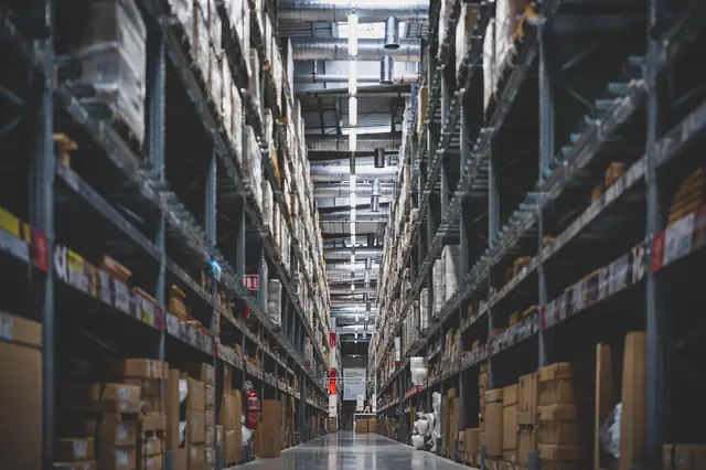 Tall warehouse aisle with shelves stacked high with goods
