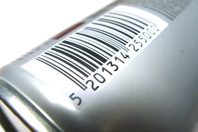 Close-up of a black-and-white barcode label on a silver metal can, the kind of SKU code scanned at a POS checkout