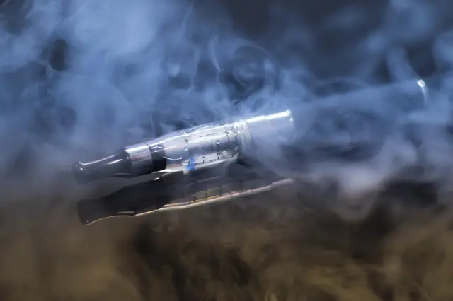 E-cigarette surrounded by drifting clouds of vapor
