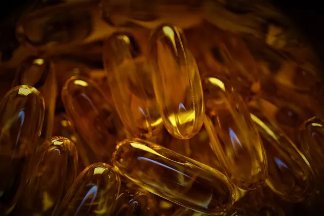 Close-up of glossy amber softgel supplement capsules piled together under warm, dramatic lighting