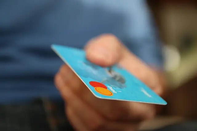 Hand holding out a blue credit card, softly blurred