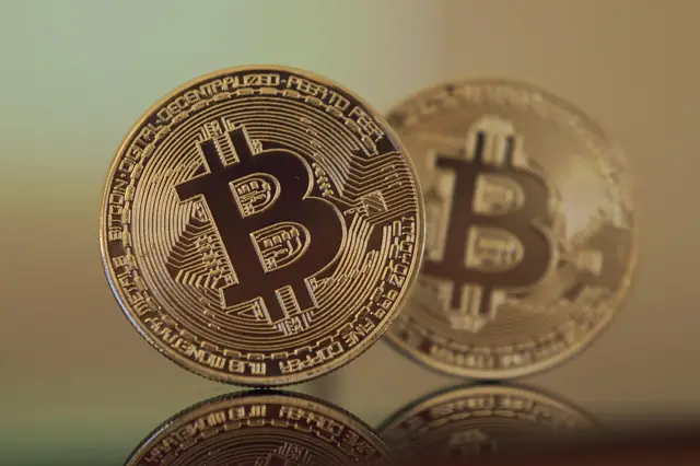 Two gold bitcoin coins standing on a reflective surface