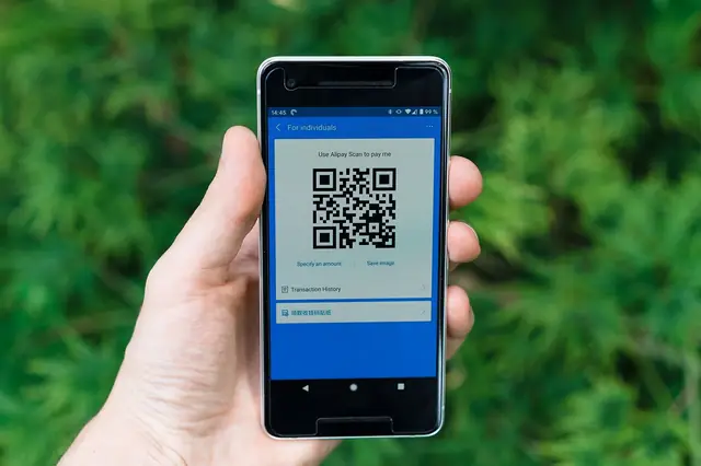 Hand holding a phone displaying a QR code payment screen