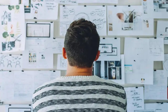 Designer facing a wall covered in sketches and layout drafts