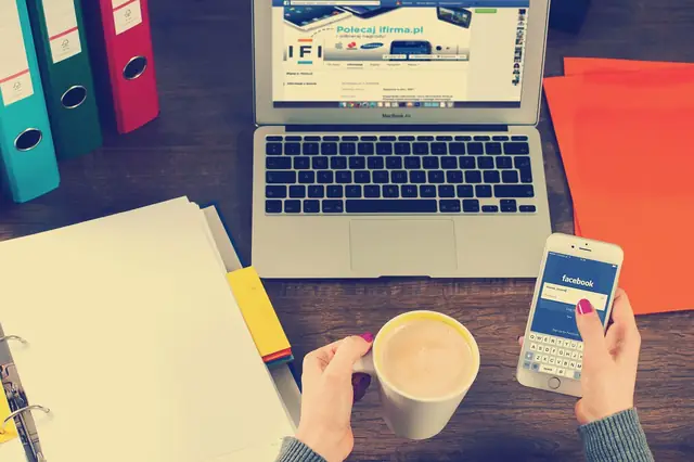 Desk with laptop, phone, coffee, folders and paperwork