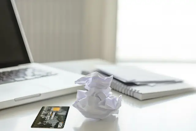 Payment card and notebook beside a laptop on a white desk
