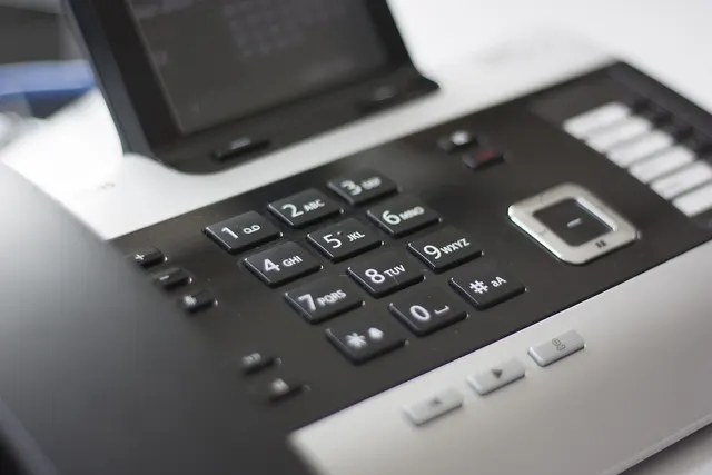Close-up of a black and silver office desk phone keypad with a display screen, as used for billing calls