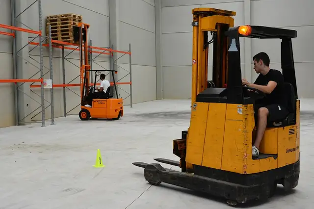 Workers driving forklifts in an empty warehouse