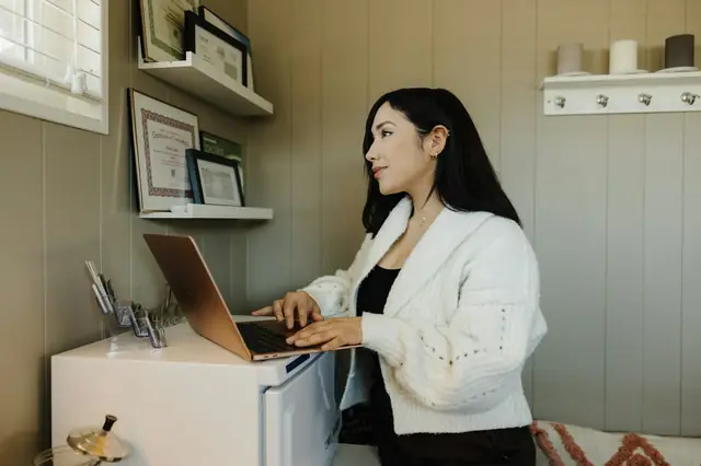 Woman typing on a laptop at a standing desk in a home office
