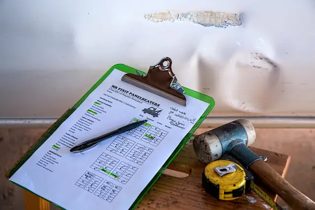 Repair checklist on a clipboard with tools by a dented car panel